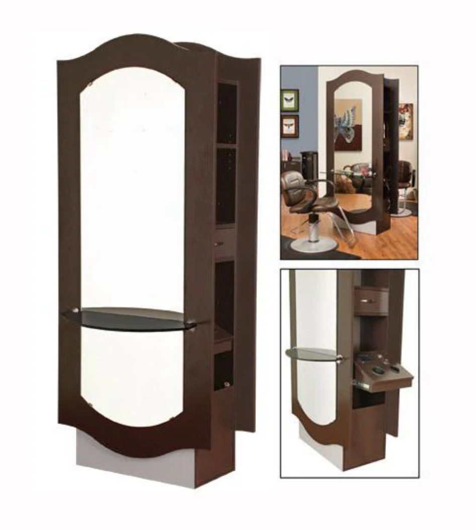 A professional styling island with a dark wood finish, featuring a large mirror, glass shelf, and storage compartments, set in a salon environment.