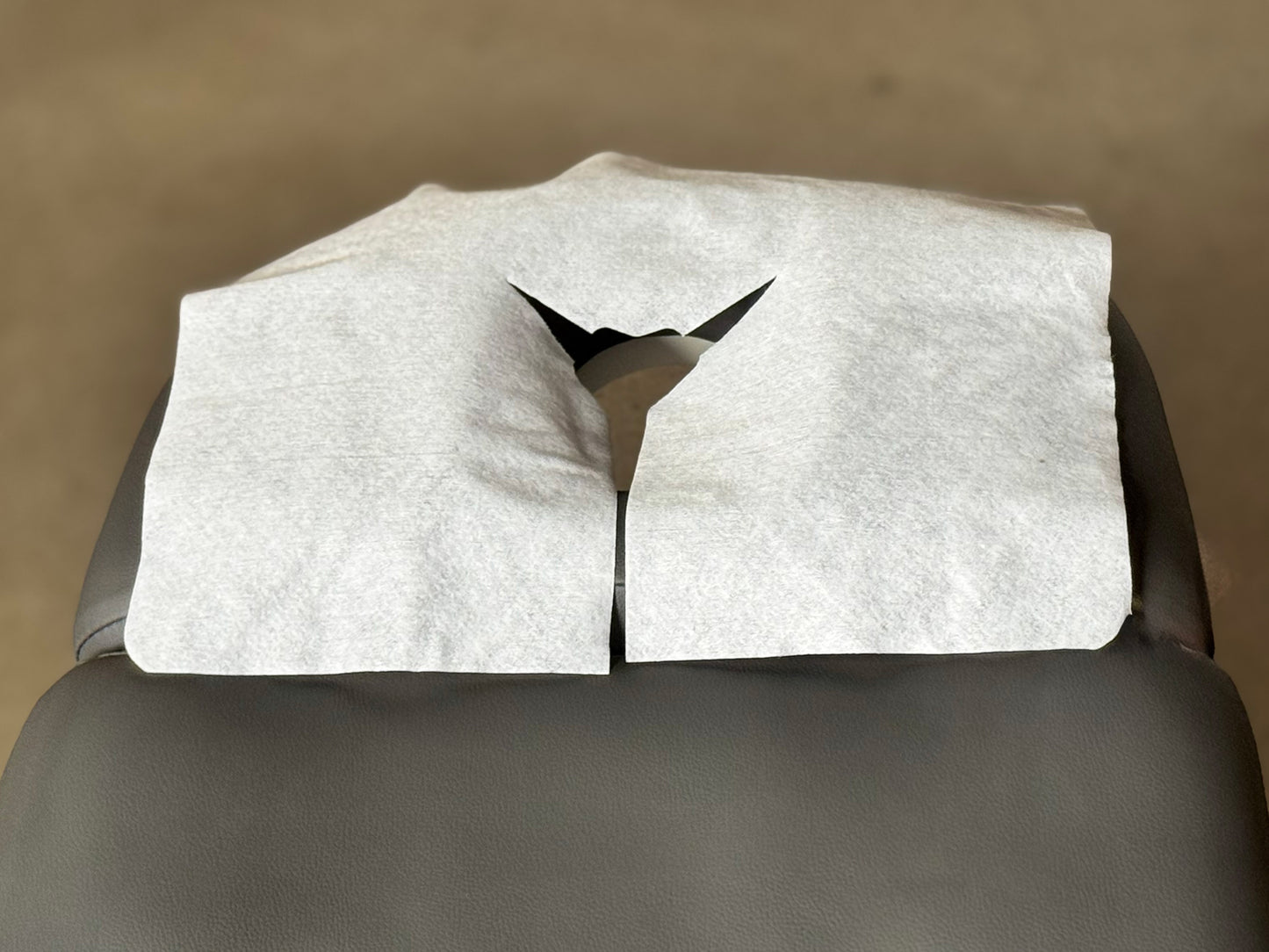 applying disposable face cradle cover on massage table headrest